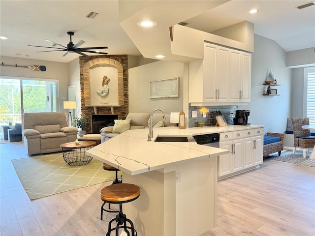 kitchen featuring ceiling fan, a sink, a peninsula, open floor plan, and light wood-style flooring