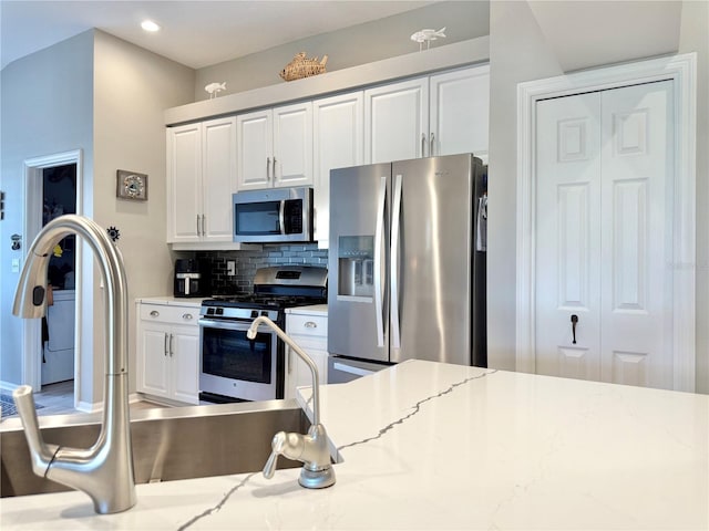 kitchen featuring decorative backsplash, appliances with stainless steel finishes, a sink, white cabinets, and recessed lighting