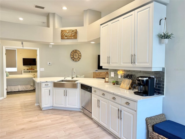 kitchen with stainless steel dishwasher, a peninsula, white cabinetry, light wood-style flooring, and backsplash