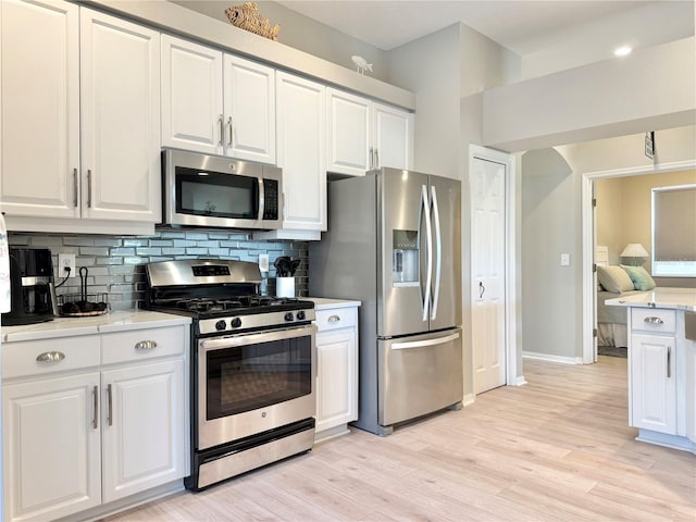 kitchen featuring light countertops, decorative backsplash, white cabinets, and stainless steel appliances
