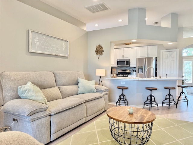 living area with visible vents, recessed lighting, light wood finished floors, and baseboards