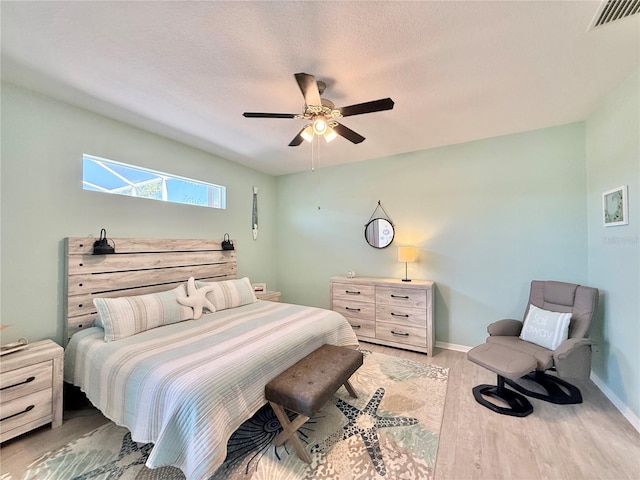 bedroom featuring visible vents, baseboards, ceiling fan, and wood finished floors