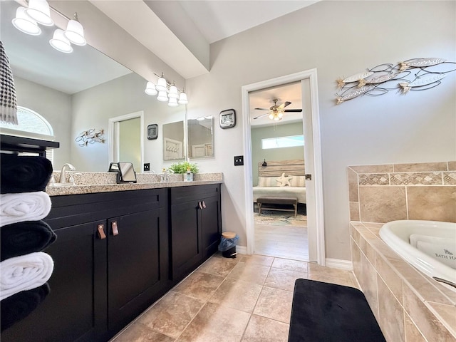 bathroom featuring ceiling fan, tiled tub, tile patterned flooring, vanity, and ensuite bathroom