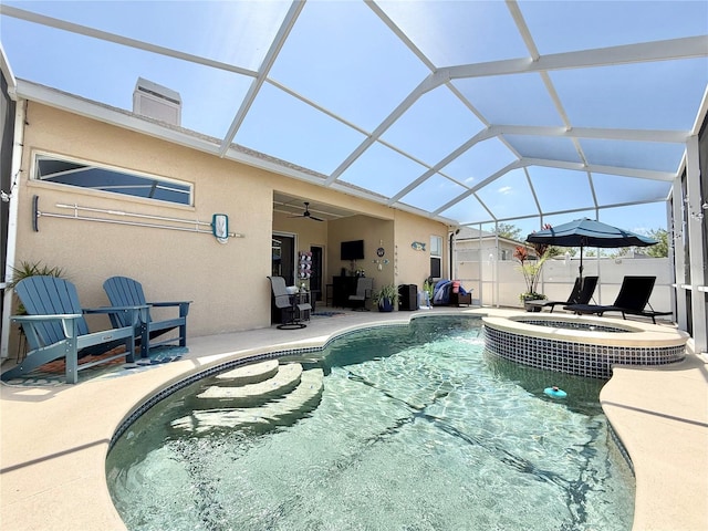view of swimming pool with ceiling fan, a patio area, a pool with connected hot tub, and glass enclosure