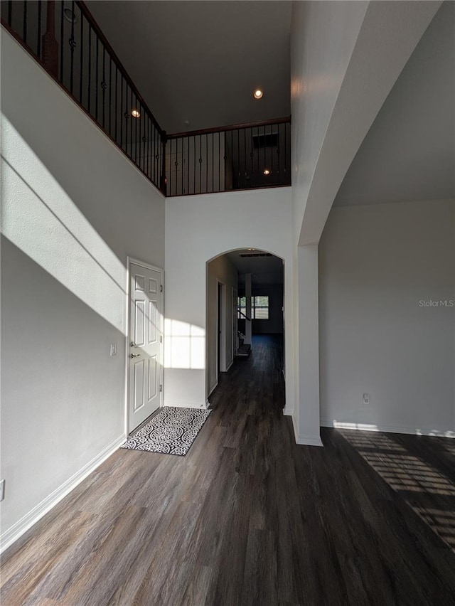 19314 Long Lake Ranch Blvd, Lutz, FL 33558 - unfurnished living room featuring arched walkways, wood finished floors, baseboards, a towering ceiling, and recessed lighting