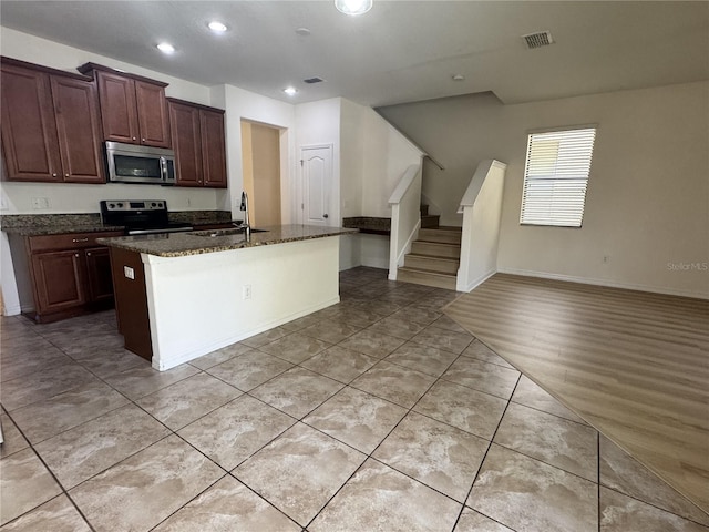 2731 Hampton Green Ln, Brandon, FL 33511 - kitchen with appliances with stainless steel finishes, dark stone counters, a center island with sink, recessed lighting, and light tile patterned flooring