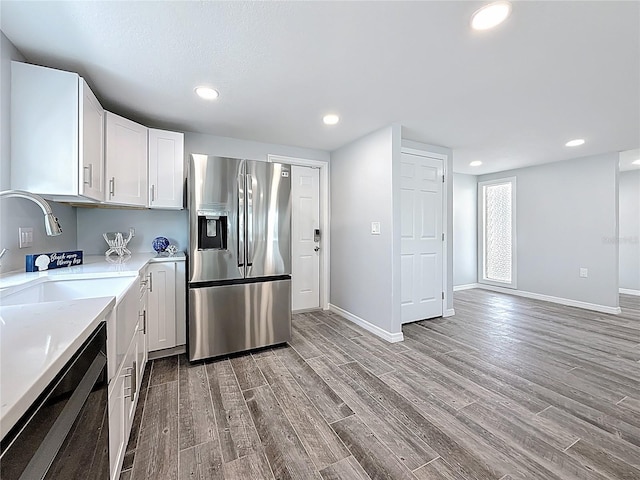 kitchen with stainless steel fridge, light countertops, light wood-style flooring, baseboards, and dishwashing machine