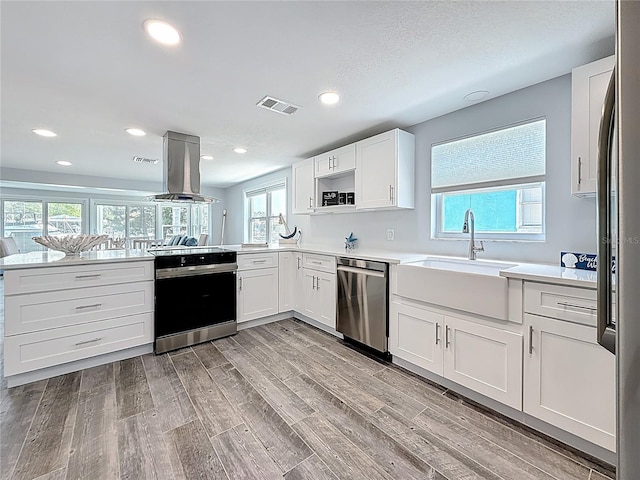 kitchen featuring dishwasher, electric stove, a peninsula, island range hood, and visible vents