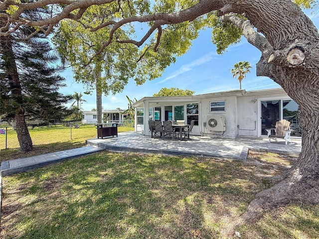 rear view of property featuring a lawn, ac unit, a patio area, fence, and stucco siding