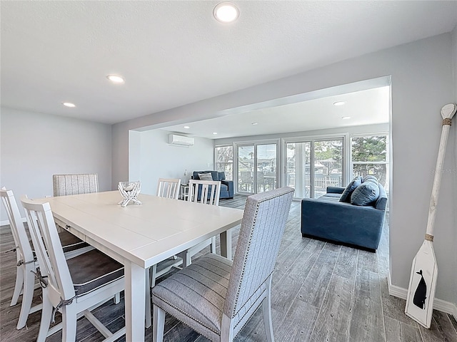 dining area featuring baseboards, recessed lighting, a wall mounted air conditioner, and wood finished floors