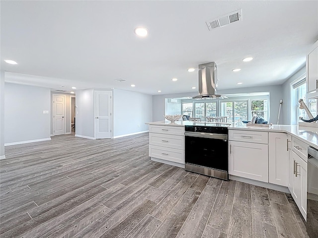 kitchen with range with electric stovetop, island range hood, visible vents, light wood-type flooring, and open floor plan