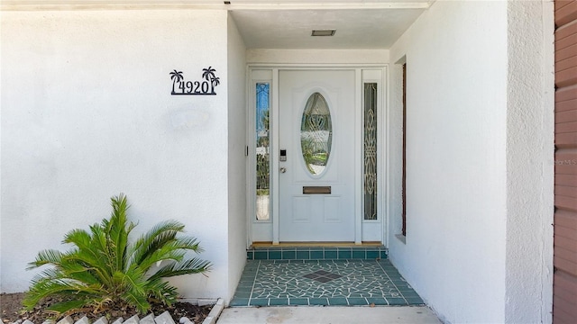 doorway to property with visible vents and stucco siding