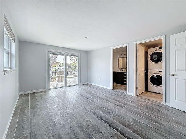 interior space featuring baseboards, stacked washer and clothes dryer, and wood finished floors