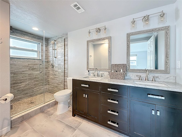 bathroom with a sink, a shower stall, toilet, and visible vents