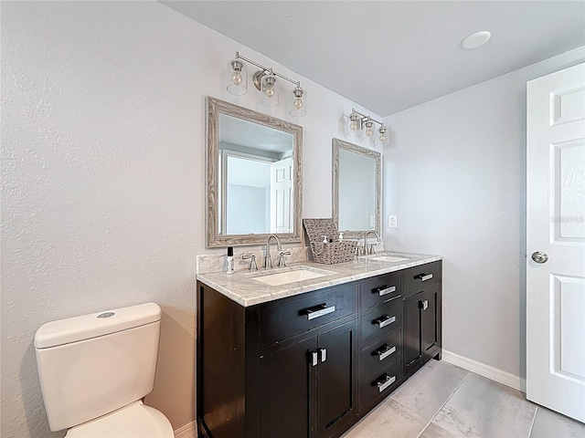 bathroom featuring double vanity, a sink, baseboards, and toilet