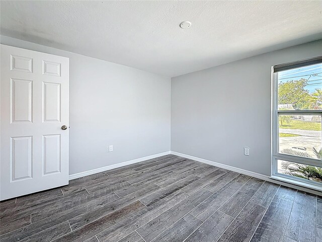 4920 Pelican Dr, New Port Richey, FL 34652 - empty room featuring dark wood-style flooring, baseboards, and a textured ceiling