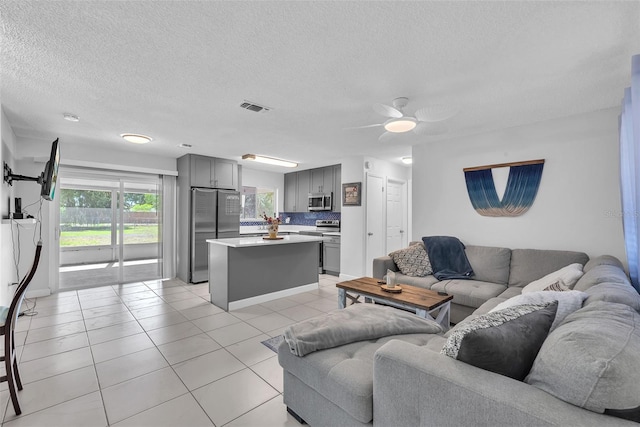 living area with light tile patterned floors, ceiling fan, a textured ceiling, and visible vents