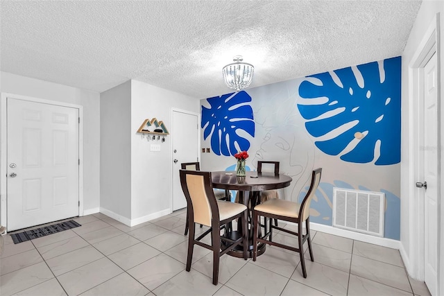 dining area with visible vents, an accent wall, baseboards, a textured ceiling, and a chandelier
