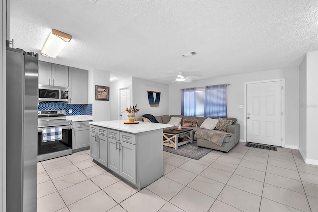 kitchen featuring visible vents, open floor plan, a textured ceiling, gray cabinets, and stainless steel appliances