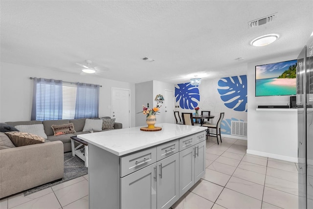 kitchen with a textured ceiling, visible vents, open floor plan, and a center island