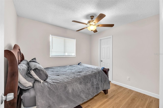 bedroom featuring a textured ceiling, baseboards, a ceiling fan, and light wood-style flooring