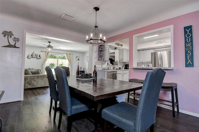 8497 137th St, Seminole, FL 33776 - dining room featuring dark wood-type flooring, a textured ceiling, baseboards, and ceiling fan with notable chandelier