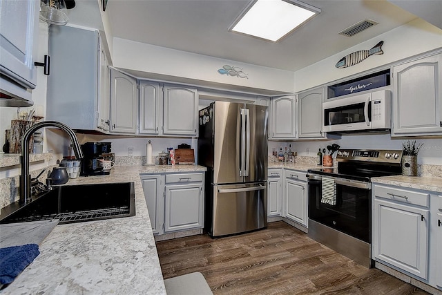 8497 137th St, Seminole, FL 33776 - kitchen with appliances with stainless steel finishes, a sink, light countertops, dark wood finished floors, and visible vents