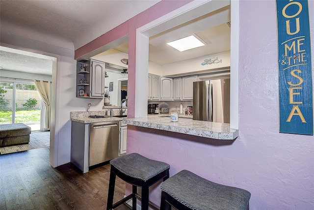 8497 137th St, Seminole, FL 33776 - kitchen with a textured wall, a breakfast bar, dark wood-style floors, light countertops, and appliances with stainless steel finishes
