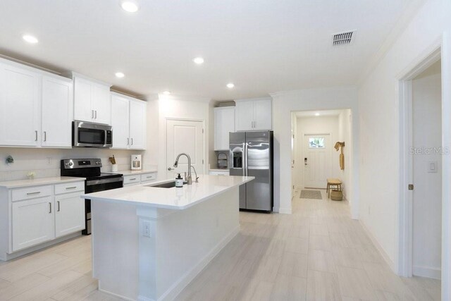 10998 Gable Dig Loop, San Antonio, FL 33576 - kitchen with a sink, a kitchen island with sink, stainless steel appliances, and white cabinetry