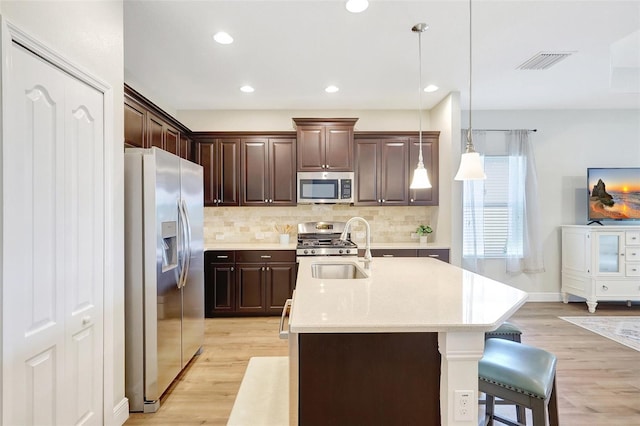 kitchen featuring a sink, appliances with stainless steel finishes, light wood-style floors, and visible vents