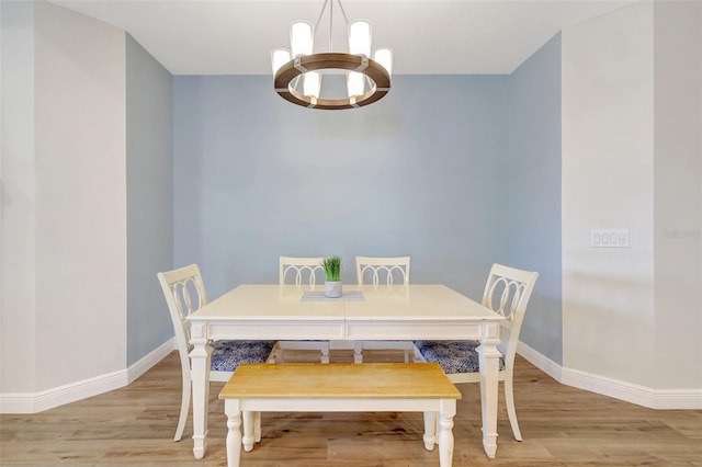 dining room with baseboards, light wood-style floors, and an inviting chandelier