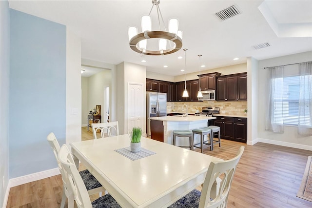 dining room featuring baseboards, visible vents, and light wood-style floors
