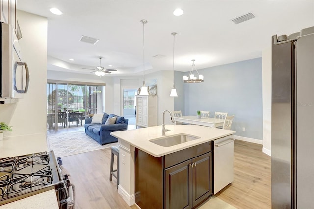 kitchen with appliances with stainless steel finishes, visible vents, a sink, and light wood-style floors