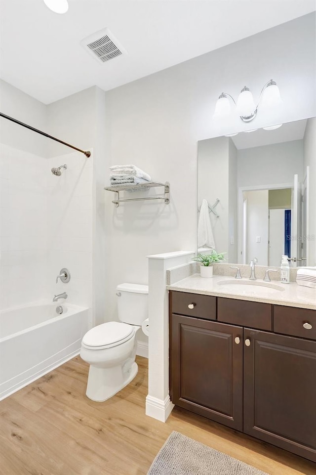 full bathroom featuring visible vents, wood finished floors, vanity, toilet, and bathing tub / shower combination