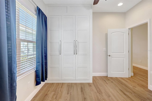 unfurnished bedroom with baseboards, a closet, and light wood-type flooring
