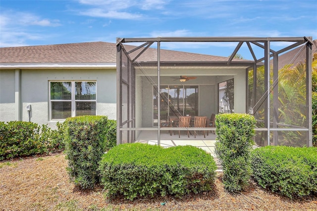 back of property with a ceiling fan, glass enclosure, stucco siding, and a patio