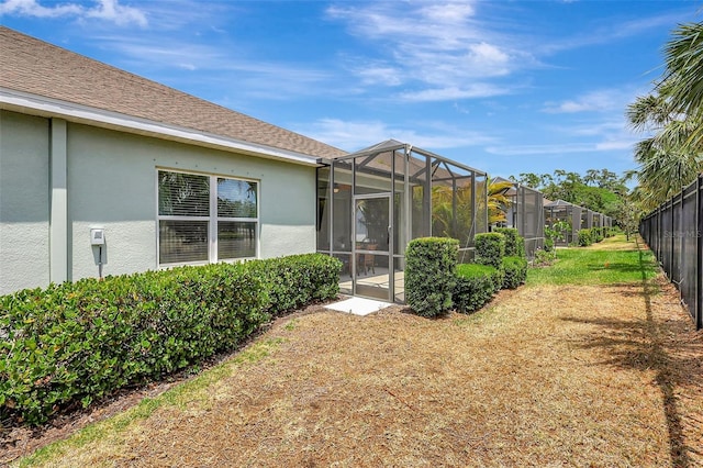 back of property featuring fence, a lanai, and stucco siding