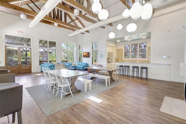 dining area with french doors, high vaulted ceiling, wood finished floors, and beam ceiling