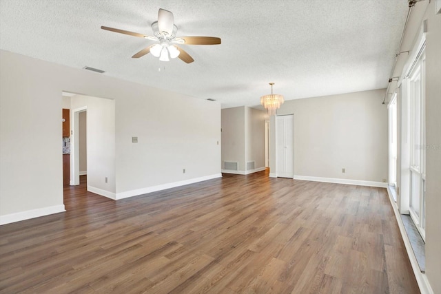 empty room with visible vents, a ceiling fan, a textured ceiling, and wood finished floors