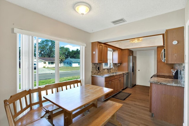 dining area featuring visible vents, a textured ceiling, and wood finished floors
