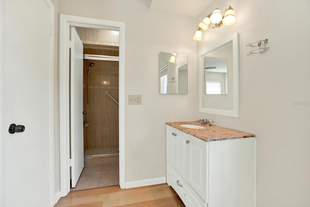 bathroom featuring vanity, baseboards, a stall shower, and wood finished floors