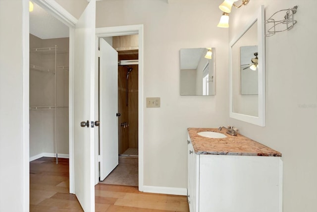 full bathroom with vanity, wood finished floors, ceiling fan, a spacious closet, and a shower stall