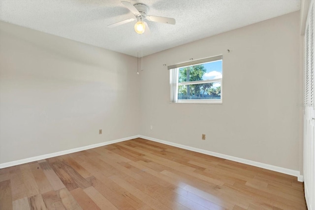 spare room featuring a textured ceiling, baseboards, a ceiling fan, and light wood-style flooring