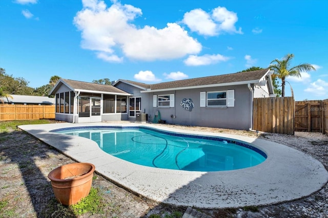 view of pool featuring a sunroom, a fenced backyard, central AC, and a fenced in pool