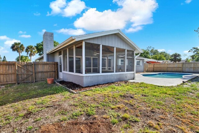 rear view of property featuring a sunroom, a fenced backyard, a fenced in pool, a chimney, and a ceiling fan