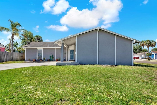 view of front of property featuring fence, stucco siding, and a front yard