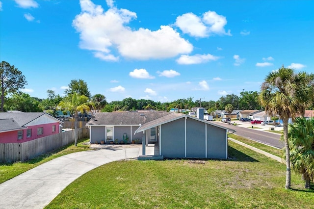 back of property featuring fence, concrete driveway, a yard, and stucco siding