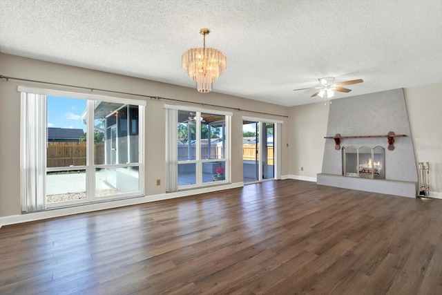 unfurnished living room featuring a warm lit fireplace, a textured ceiling, and wood finished floors