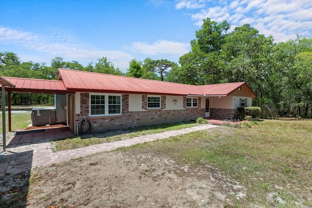 ranch-style home featuring a hot tub, brick siding, a front yard, a carport, and metal roof