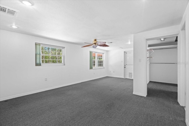 unfurnished bedroom with baseboards, visible vents, multiple windows, and dark colored carpet